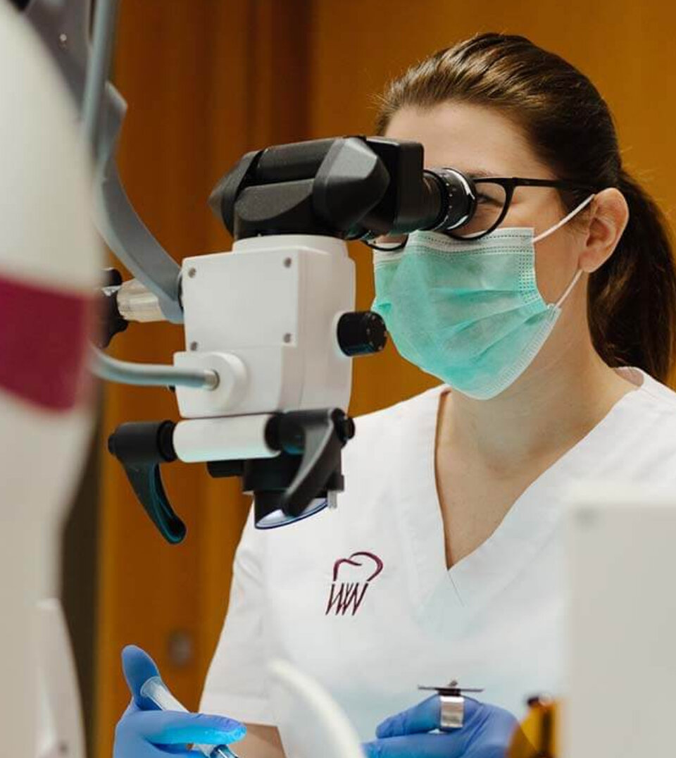 dentystka z mikroskopem stomatologicznym podczas zabiegu endodoncji